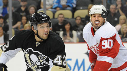 Penguins forward Eric Tangradi battles for loose puck with Red Wings forward Mike Modano.
