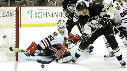 Blackhawks goaltender  Hannu Toivonen makes a save against Penguins forward Nick Johnson.
