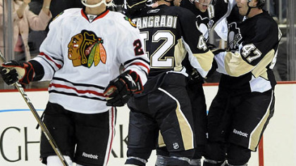 Blackhawks left winger Jeremy Morin  watches the replay as Penguins forward Eric Tangradi, Simon Despres, right, and Evgeni Malkin celebrate after Malkin scored during the first period.