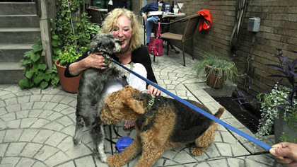 Aleppo's Carolyn Smith gets a kiss from Samson Amadeus, left, as her own dog, Sophie, gets social, too, at the Bowl and Biscuit Night at Cassis restaurant on the North Side.