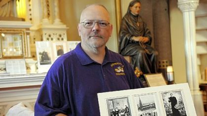 Derris Jeffcoat, sancristan and church historian at St. Patrick-St. Stanislaus Kostka parish in the Strip District, holds photos of St. Philomena parish, center, with two of its fathers, Blessed Francis Seelos, left, and St. John Neumann. In the back right is a statue of Blessed Frances Siedliska, founder of the Sisters of the Holy Family of Nazareth.