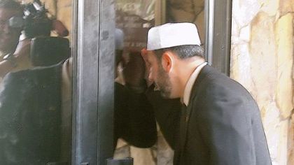 Imam Muhammad Musri, of the Islamic Society of Central Florida, peeks into the window at the Dove World Outreach Center in Gainesville, Fla. on Wednesday. He later met with  Terry Jones, pastor of the church, who is under pressure to drop his plan to burn copies of the Muslim holy book Saturday.
