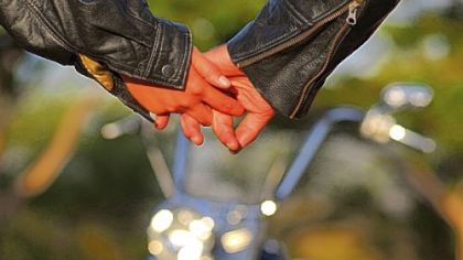 Couple holding hands with a motorcycle in the background
