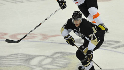 Penguins forward Evgeni Malkin moves the puck as Flyers forward Darroll Powe chases him in the second period.