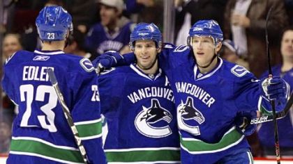 Vancouver Canuck Ryan Kesler, center, celebrates his goal with teammates Alexander Edler, left, and Christian Ehrhoff during a March game. Kesler is the cover athlete of the video game "NHL 2K11," due out next week.