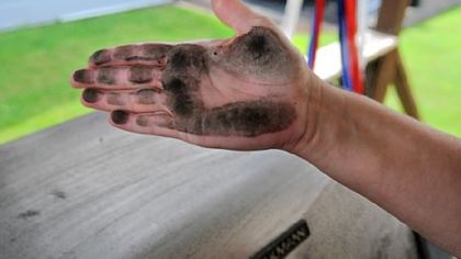 Stacy Beisler's hand is covered with black soot she wiped from her backyard grill, which she had cleaned two days earlier.