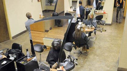 Emilio Cornacchione, bottom right, proprietor of Izzazu salon, works on client Denis Robinson's hair in the salon's new digs next to the Capital Grill on Fifth Ave.