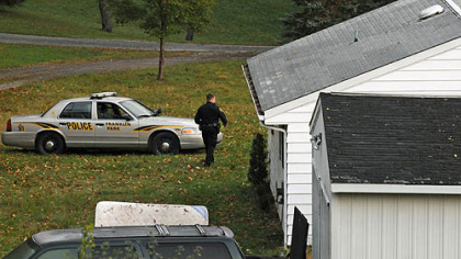 A Franklin Park police officer walks behind a home along Nickelson Road after a chase and manhunt in the early morning hours Monday. A system for growing marijuana was found in the basement.