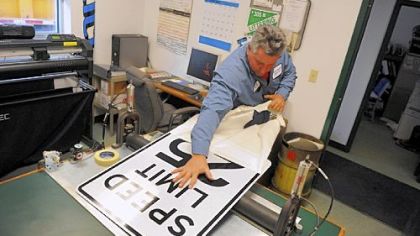 Sign maker Pete Shandrick pulls a cover off of a speed limit sign he created inside his office in the Moon Public Works garage.