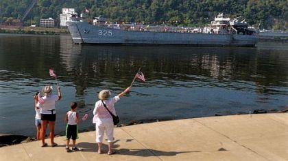 People wave flags for the LST 325 as it heads toward the North Shore of Pittsburgh.