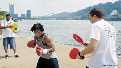 Monty Meza-Clay works out with paddles wielded by head trainer Tom Yankello at an Aug. 20 media session at the Rivers Casino to promote his upcoming Super Featherweight fight against  Allen "The American Boy" Litzau on August 28. At left is assistant trainer Kevin Corlew.