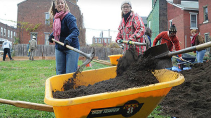 Lyn Hyde, left, and Helen Perilloux, who both live in the Uptown area, and other volunteers work on a new community garden on Tustin Street.