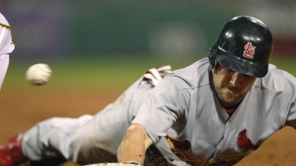 The ball gets away from Pirates first baseman Garrett Jones as the Cardinals' Skip Schumaker dives back to first on a pickoff attempt by  pitcher Charlie Morton in the second inning.