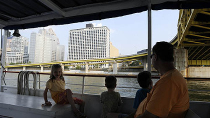 Regis Kudrav, of Washington, Pa., with his children Olivia, 7, Clark, 4, and Grant, 8, ride on the Allegheny River.