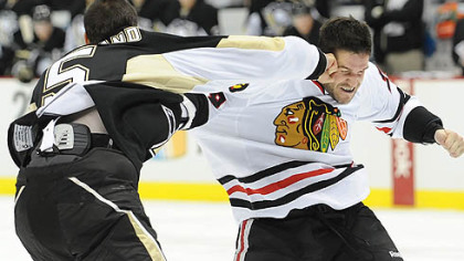 Penguins defenseman Deryk Engelland connects with a right to the head of Blackhawks forward Jake Dowell.