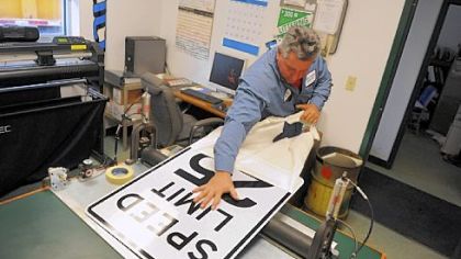 Sign maker Pete Shandrick pulls a cover off a speed limit sign he created inside his office in the Moon public works garage. Mr. Shandrick has been an employee of the township public works department for 22 years.