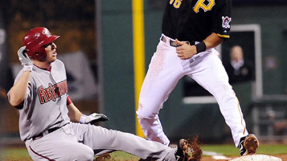The Diamondbacks' Stephen Drew slides back safely to first base as Pirates first baseman Garrett Jones misses the ball during the third inning.