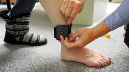 Frank Scherer, manager of the monitoring program at the Allegheny County Adult Probation Department, demonstrates how to apply an ankle bracelet transmitter at its facility on Mt. Lebanon Boulevard in Castle Shannon.