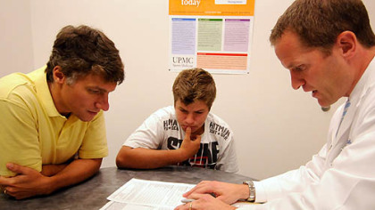 Michael Collins, right, reviews the comparison of concussion test scores with Gaige Pavlocak and his father, Jeff, in September during their second visit with Dr. Collins at the UPMC Sports Medicine complex on Pittsburgh's South Side.