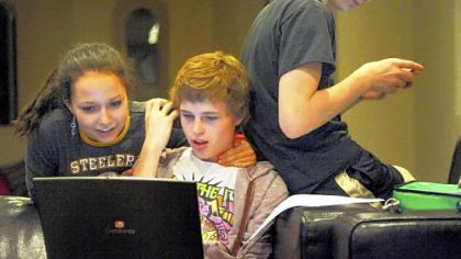 Elizabeth Truell, 15, looks over Cameron Clark's shoulder while he's on his computer as Seth Klein-Tooley, 13, of Spokane, Washington, checks his phone at the Pittsburgh Ballet Theatre's Byham house for out-of-town students.