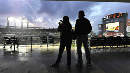 Mary Spadoni, from the Astoria neighborhood of the Queens borough of New York, photographs the clearing storm clouds over Citi Field with her friend, Matthew Thompson, also from Astoria.