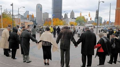 People hold hands during the opening prayer at the Hill District Freedom Corner on Friday for the news conference on the Prison Ministries and Divine Interventions'  Prison Society's Building Bridges program.