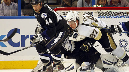 Penguins captain Sidney Crosby Lighting goaltender Dan Ellis as he's checked by forward Nate Thompson.
