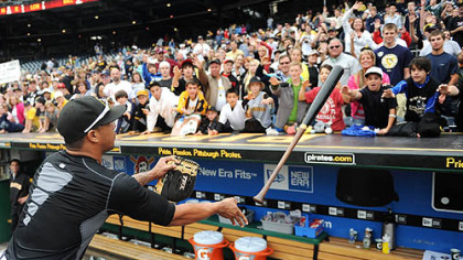 Pedro Alvarez flips a bat to the top of the Pirates' dugout for a fan after the game Sunday. Several players tossed equipment and signed autographs.