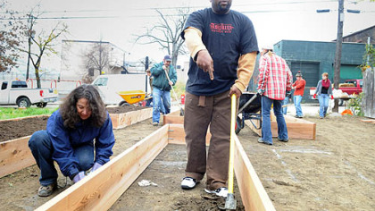 Jeanne McNutt, left, executive director of Uptown Partners, Nate Hurt, 45, of Uptown and other volunteers work on a new community garden on Tustin Street.