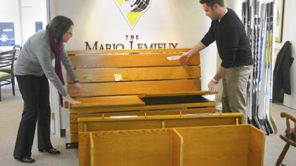 Nancy Angus, executive director of the Mario Lemieux Foundation, left, and Drew Parish, marketing manager for the foundation, pull apart the pieces of Mario Lemieux's locker. The proceeds from auctioning the locker will go toward raising money for an Austin's Playroom project at the Walter Reed National Military Medical Center in Bethesda, Md.