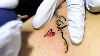 Keith Reed, a tattoo artist at X-treme Ink tattoo in West Chester, Pa., finishes the Paul McCartney signature tattoo on Rose Ann Belluso. Belluso got her back signed by McCartney during a concert Sunday night in Philadelphia, and decided to have the signature tattooed onto her back permanently.