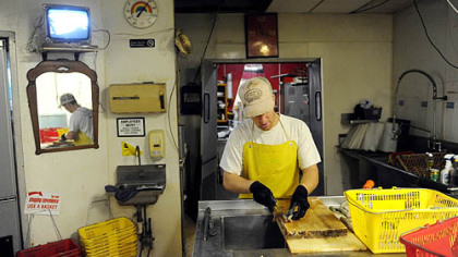 Aaron Mathers scales and fillets fish at his family's shop, The Last Fisherman, in Erie.